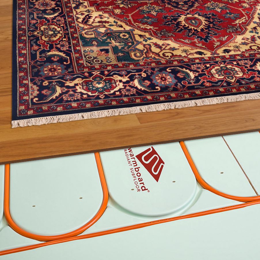 Warmboard panel with pipe in its channels, partly covered by timber flooring and a rug