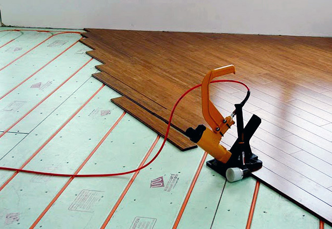 Timber flooring being laid over Warmboard panels with the pipe already in place
